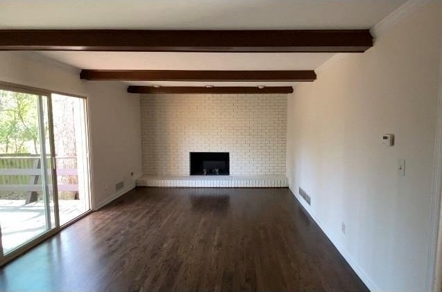 unfurnished living room featuring visible vents, baseboards, beam ceiling, a fireplace, and dark wood-style flooring