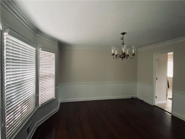 empty room with an inviting chandelier, wood finished floors, baseboards, and ornamental molding