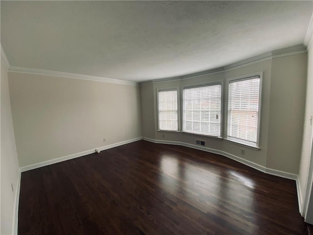 spare room with visible vents, dark wood-type flooring, ornamental molding, a textured ceiling, and baseboards