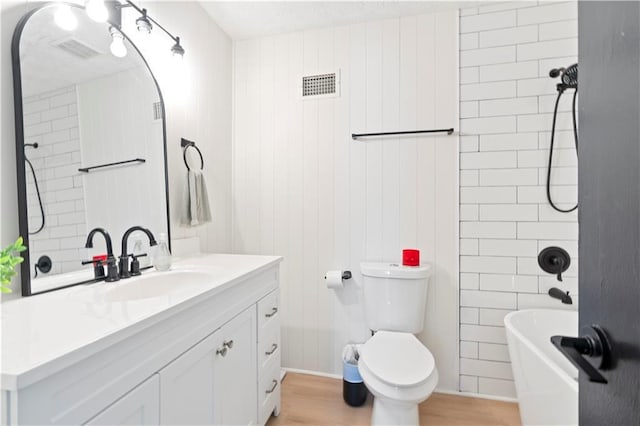 bathroom with a tub to relax in, toilet, wood-type flooring, and vanity