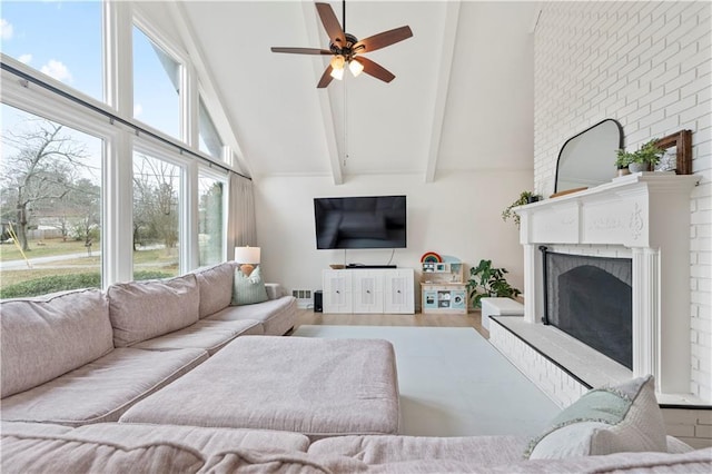 living room with high vaulted ceiling, beamed ceiling, hardwood / wood-style flooring, ceiling fan, and a brick fireplace