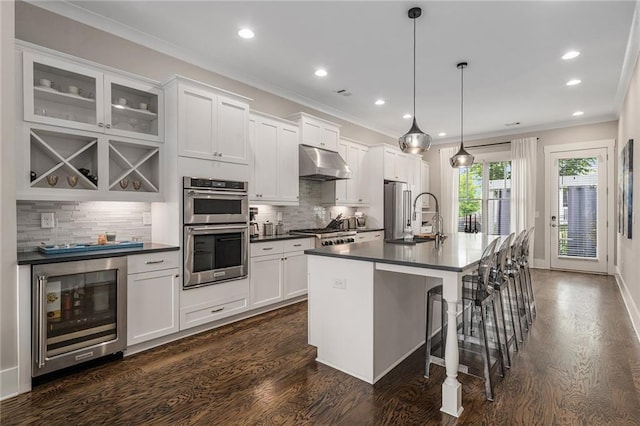 kitchen with under cabinet range hood, a sink, dark countertops, stainless steel appliances, and wine cooler