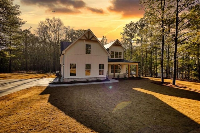 back house at dusk with a lawn and a porch