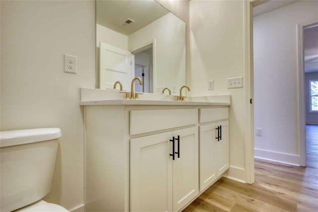 bathroom featuring wood-type flooring, vanity, and toilet