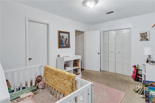 carpeted bedroom with a textured ceiling, a closet, and visible vents