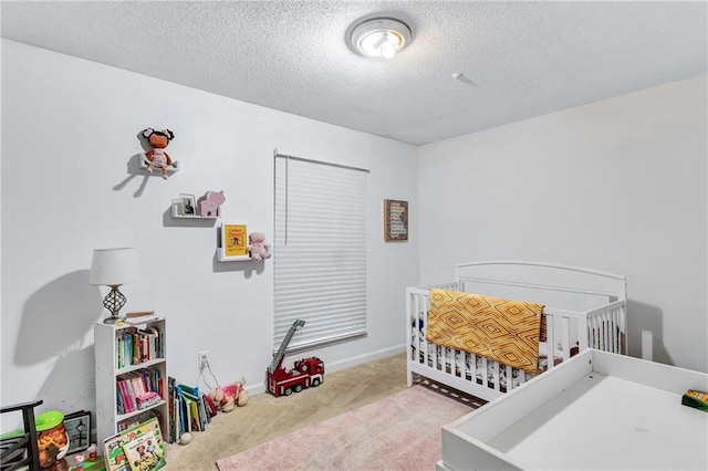 carpeted bedroom featuring a nursery area, a textured ceiling, and baseboards