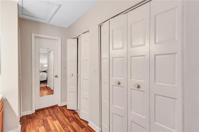 hall with attic access, baseboards, and wood finished floors