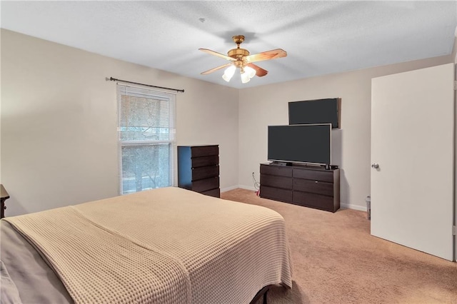 bedroom with ceiling fan, baseboards, a textured ceiling, and light colored carpet