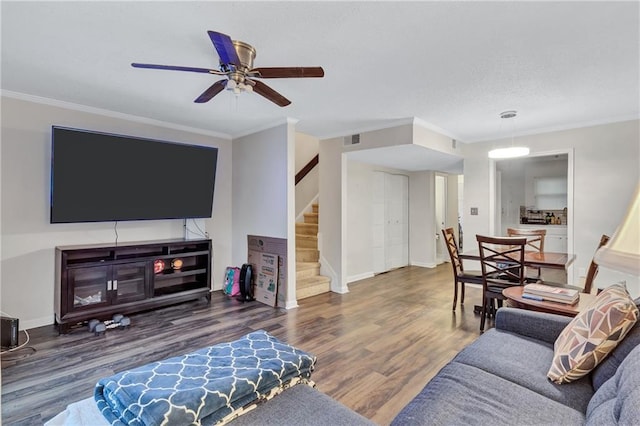 living area featuring stairway, wood finished floors, and crown molding