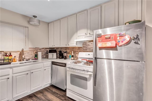 kitchen featuring stainless steel appliances, light countertops, a sink, and under cabinet range hood