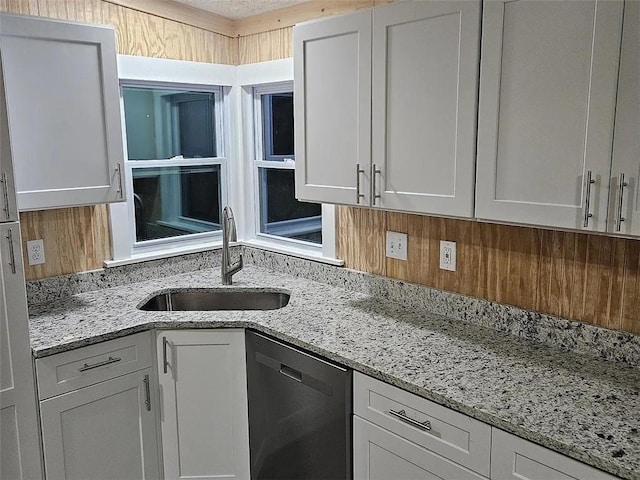 kitchen featuring light stone countertops, sink, white cabinetry, and stainless steel dishwasher