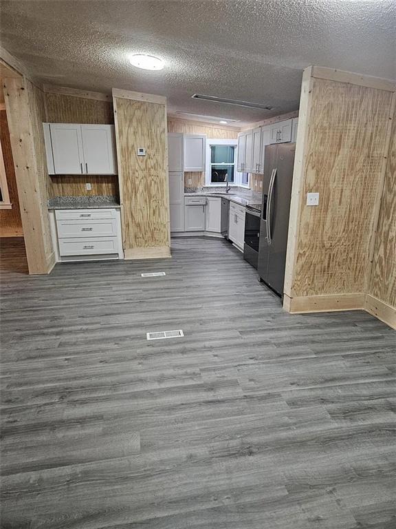 kitchen featuring white cabinets, a textured ceiling, dark wood-type flooring, and stainless steel appliances