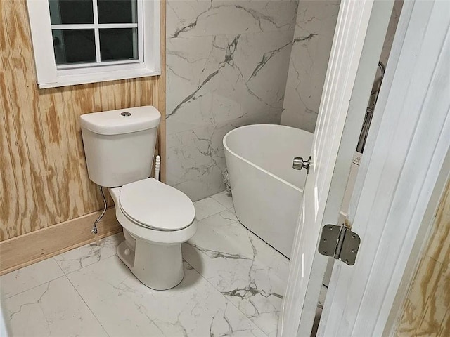 bathroom featuring a washtub, wooden walls, and toilet