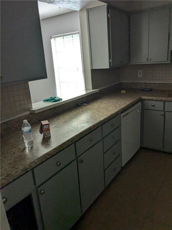 kitchen featuring dishwasher, dark countertops, and gray cabinetry