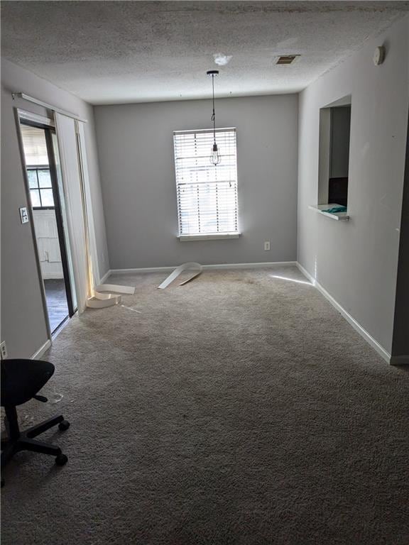 spare room featuring carpet floors, visible vents, a textured ceiling, and baseboards