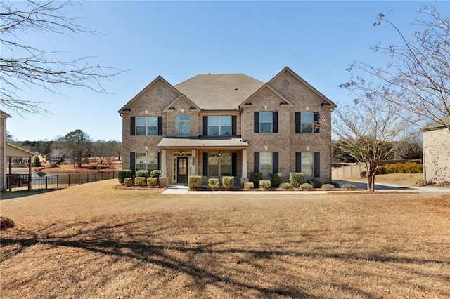 view of front of home with a front yard, fence, and brick siding