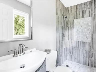 bathroom with vanity, toilet, and tiled shower