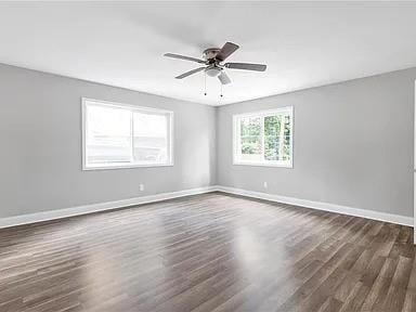 empty room featuring baseboards, dark wood finished floors, and a ceiling fan