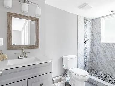 bathroom featuring a shower stall, vanity, and toilet