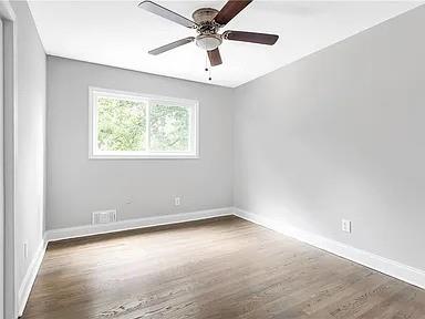 unfurnished room with baseboards, a ceiling fan, visible vents, and wood finished floors