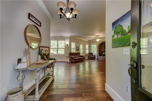 foyer entrance with ceiling fan with notable chandelier, dark wood-type flooring, and crown molding