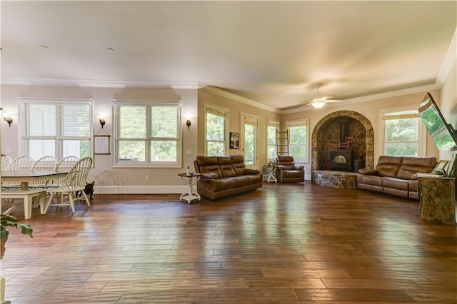 living room featuring dark hardwood / wood-style flooring, a wood stove, ceiling fan, and crown molding