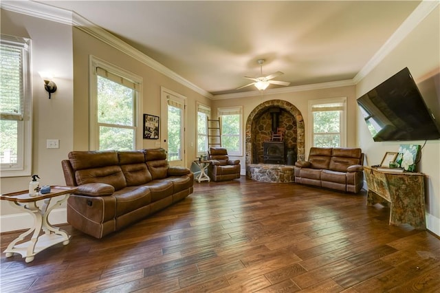 living room with a wood stove, dark wood-type flooring, ceiling fan, and crown molding