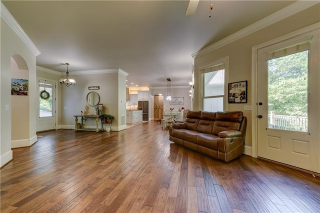 living room featuring ceiling fan with notable chandelier, wood-type flooring, plenty of natural light, and crown molding