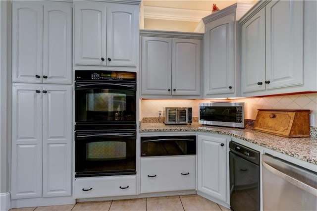 kitchen featuring light tile patterned flooring, white cabinetry, light stone counters, appliances with stainless steel finishes, and decorative backsplash