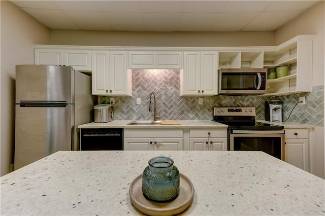 kitchen with white cabinetry, decorative backsplash, stainless steel appliances, and sink