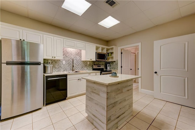 kitchen with sink, appliances with stainless steel finishes, light tile patterned floors, white cabinets, and decorative backsplash