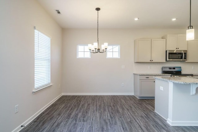 kitchen with visible vents, light stone counters, appliances with stainless steel finishes, baseboards, and dark wood-style flooring