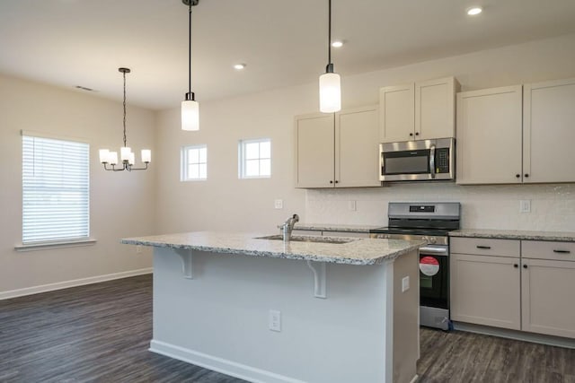 kitchen featuring a sink, baseboards, decorative backsplash, appliances with stainless steel finishes, and a kitchen island with sink