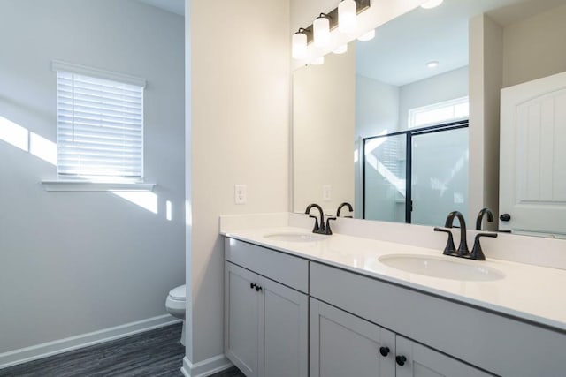 full bath with a stall shower, toilet, baseboards, and a sink