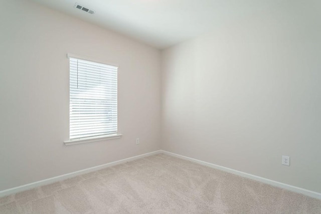 spare room featuring baseboards, visible vents, and light carpet