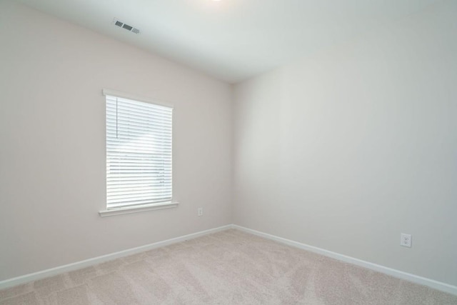 spare room featuring visible vents, light colored carpet, and baseboards