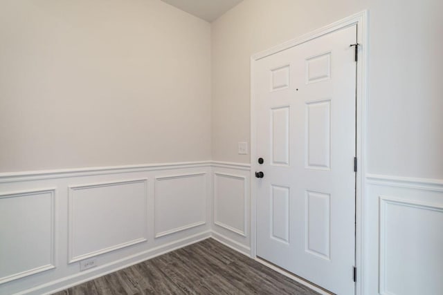 doorway to outside featuring a decorative wall, dark wood-style floors, and a wainscoted wall