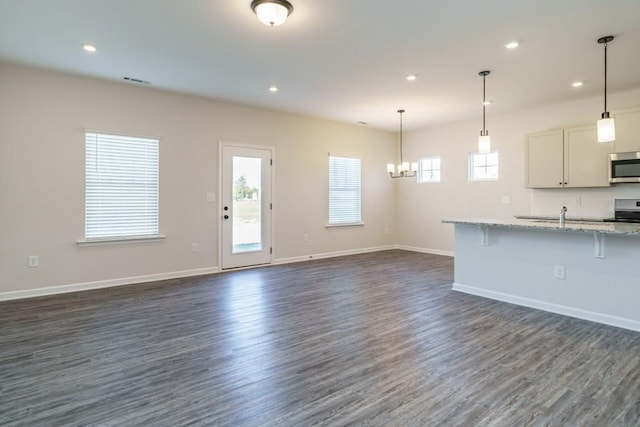 kitchen with dark wood-type flooring, baseboards, open floor plan, and stainless steel appliances