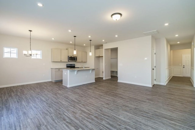 kitchen with a center island with sink, a breakfast bar, dark wood-style flooring, stainless steel appliances, and open floor plan