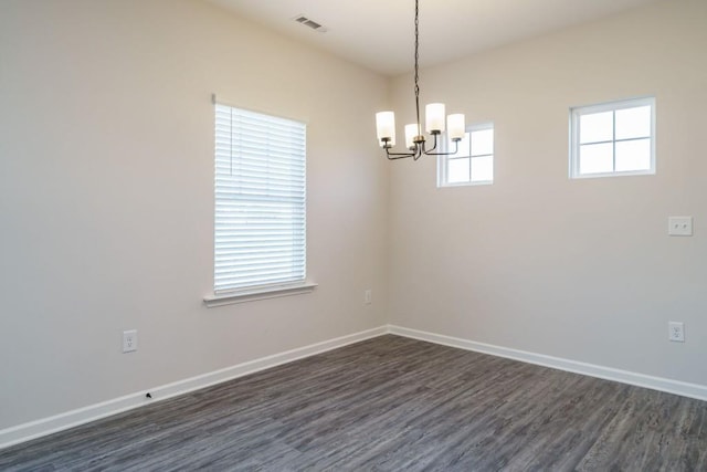 spare room featuring dark wood-style floors, visible vents, an inviting chandelier, and baseboards