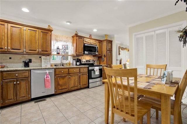 103 Mims Dr, Calhoun, GA 30701 - kitchen with appliances with stainless steel finishes, a sink, tasteful backsplash, brown cabinetry, and ornamental molding