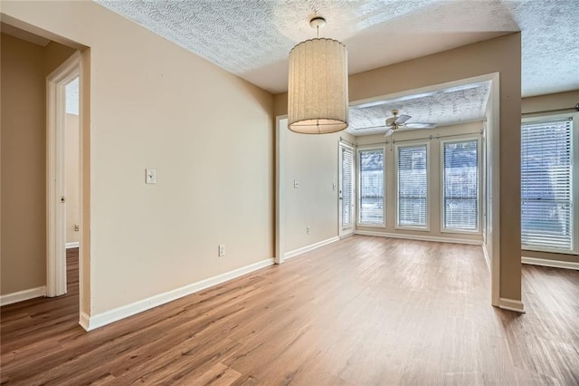 interior space featuring a textured ceiling, baseboards, and wood finished floors