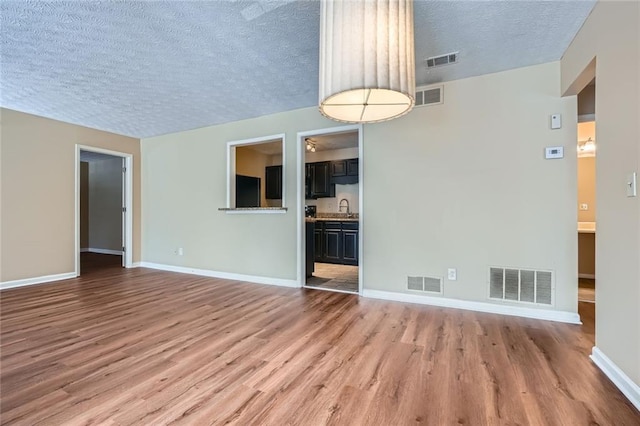 unfurnished living room featuring visible vents and a sink