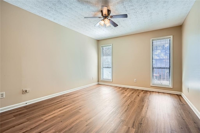 spare room featuring a textured ceiling, baseboards, and wood finished floors