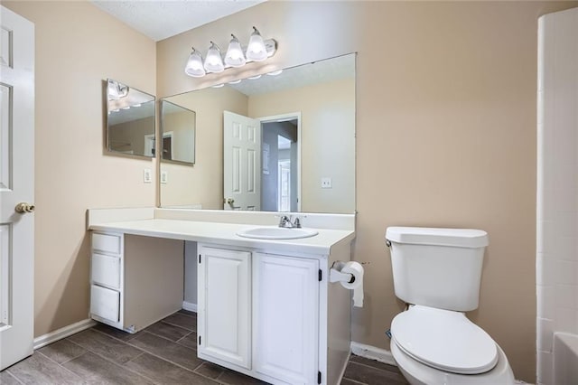 bathroom featuring wood finish floors, toilet, vanity, and baseboards