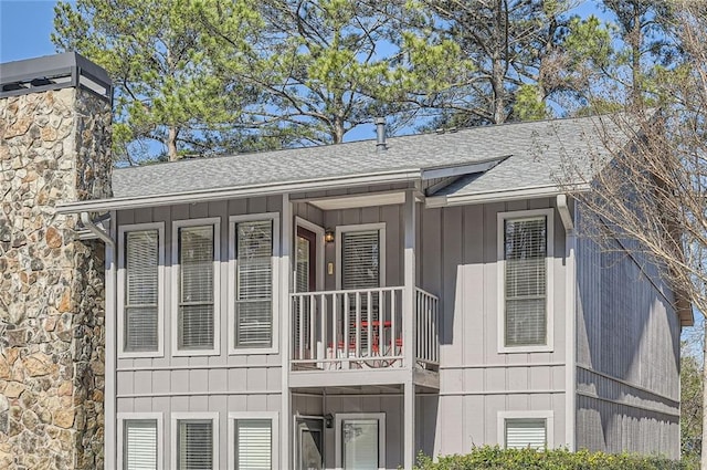 exterior space with a shingled roof and a balcony