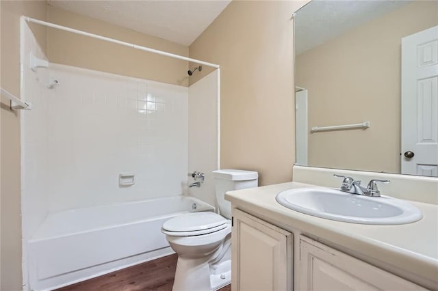 full bathroom with vanity, wood finished floors, a textured ceiling, shower / bathing tub combination, and toilet