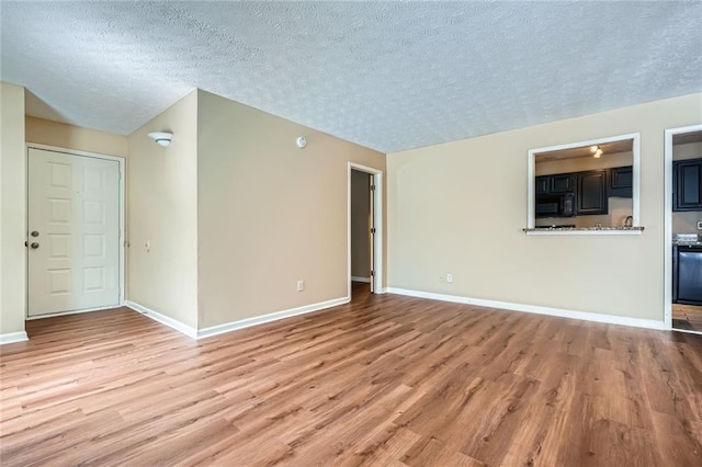 unfurnished living room featuring a textured ceiling, light wood-type flooring, and baseboards