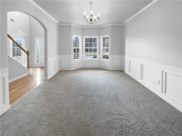 spare room featuring ornamental molding, light colored carpet, and a chandelier