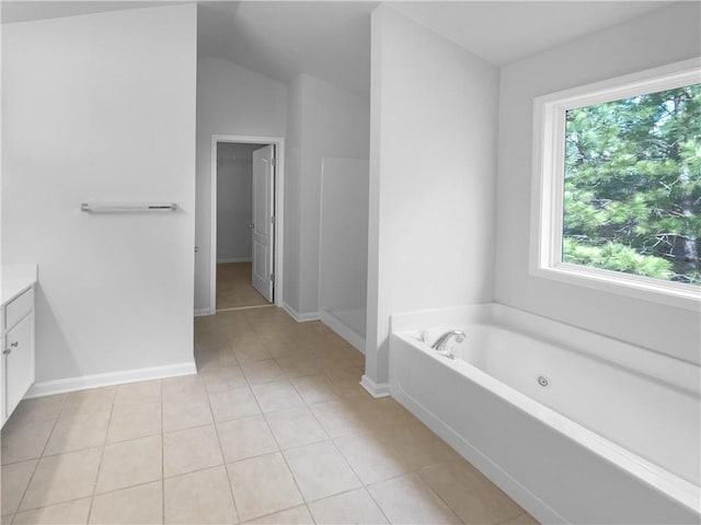 bathroom featuring a tub to relax in, vanity, tile patterned flooring, and lofted ceiling